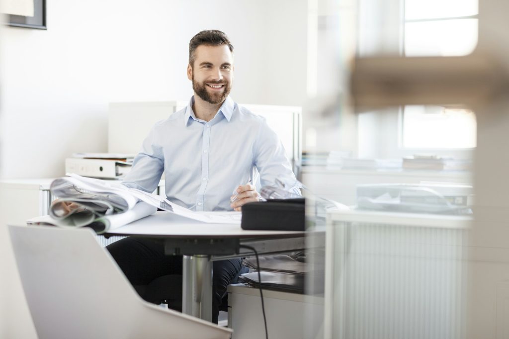 Smiling man at desk with construction plans